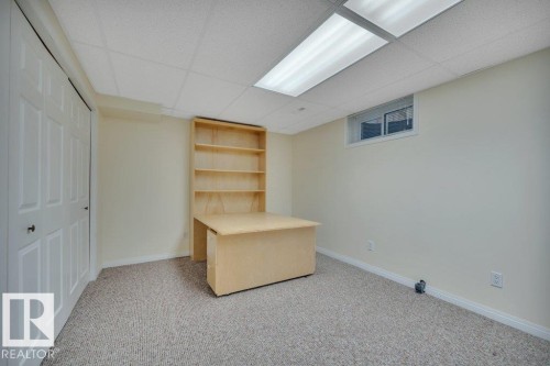 Room featuring light-colored wall-to-wall carpeting, a drop ceiling with fluorescent lighting, and a window - 18227 76 Avenue, Edmonton, AB - Indoor