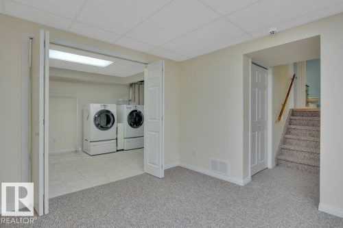 Dedicated laundry area featuring tile flooring, bi-fold doors, and a fluorescent ceiling light fixture - 18227 76 Avenue, Edmonton, AB - Indoor Photo Showing Laundry Room