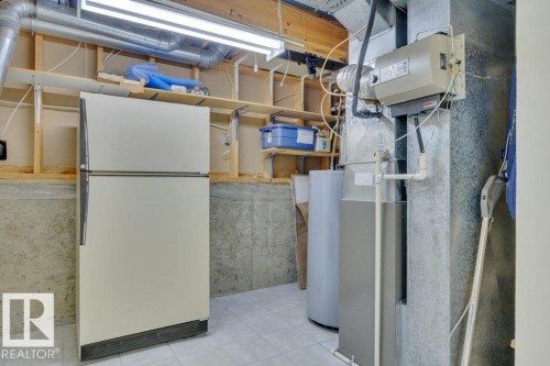 Utility space featuring concrete walls, tile flooring, exposed wood ceiling joists, and a fluorescent light fixture - 18227 76 Avenue, Edmonton, AB - Indoor Photo Showing Basement