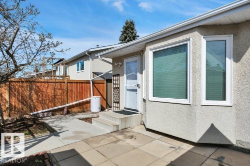 Bay window with white trim, stucco exterior finish, concrete patio, and fenced backyard - 18227 76 Avenue, Edmonton, AB - Outdoor
