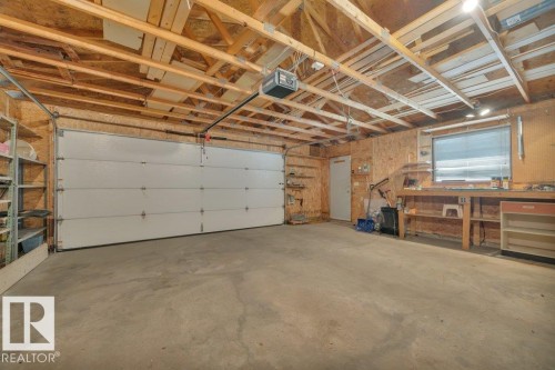 Spacious garage featuring a concrete floor, exposed wood beam ceiling, and a large white overhead door - 18227 76 Avenue, Edmonton, AB - Indoor Photo Showing Garage