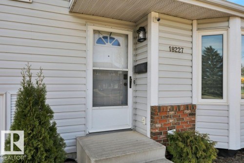 Entryway featuring light-colored siding, a white front door with a storm door, and a concrete stoop - 18227 76 Avenue, Edmonton, AB - Outdoor With Exterior