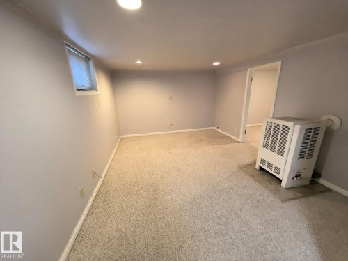 Spacious room featuring neutral carpeting, recessed lighting, a horizontal window with blinds, and painted walls - 10815 68 Avenue, Edmonton, AB - Indoor