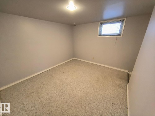 Carpeted room featuring a single window with horizontal blinds and a ceiling-mounted light fixture - 10815 68 Avenue, Edmonton, AB - Indoor Photo Showing Other Room