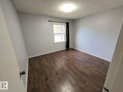 Spacious room featuring wood-finish flooring, light gray wall paint, and white baseboards - 10815 68 Avenue, Edmonton, AB - Indoor Photo Showing Other Room