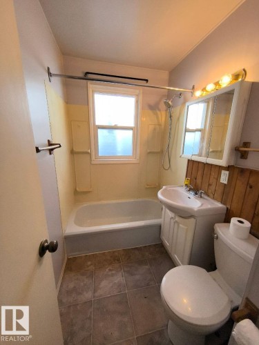Bathroom featuring a single window, a built-in bathtub with shower, a vanity sink with cabinet storage, and tile flooring - 10815 68 Avenue, Edmonton, AB - Indoor Photo Showing Bathroom