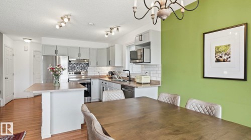 Kitchen with wood-finish flooring, light grey cabinetry, a white subway tile backsplash, and stainless steel appliances - 80 287 Macewan Road, Edmonton, AB - Indoor