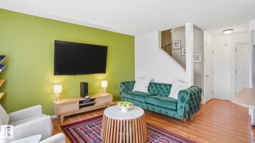 Open-concept living space with wood-finish flooring, a contemporary staircase, and a white ceiling - 80 287 Macewan Road, Edmonton, AB - Indoor Photo Showing Living Room
