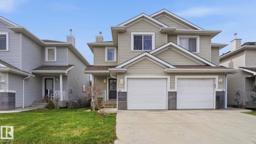 Multi-story residence featuring light-colored siding, a two-car garage with white doors, and a concrete driveway - 80 287 Macewan Road, Edmonton, AB - Outdoor With Facade