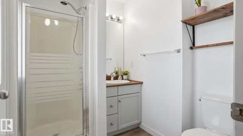 Three-piece bath with a glass-enclosed shower featuring a handheld showerhead - 80 287 Macewan Road, Edmonton, AB - Indoor Photo Showing Bathroom