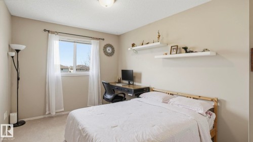 Carpeted room featuring a double-pane window with white trim, two white floating shelves, and a ceiling-mounted light fixture - 80 287 Macewan Road, Edmonton, AB - Indoor Photo Showing Bedroom