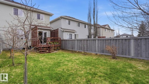 Manicured backyard featuring a wooden privacy fence, a multi-level wooden deck with steps, and a sliding glass door entry to the home - 80 287 Macewan Road, Edmonton, AB - Outdoor