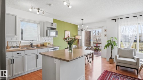 Open-concept kitchen and living area featuring wood-finish flooring - 80 287 Macewan Road, Edmonton, AB - Indoor Photo Showing Kitchen With Double Sink