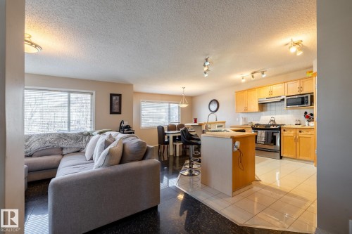 Open-concept living area featuring a kitchen with light wood cabinetry, stainless steel appliances, and tile flooring - 55 Lamplight Cove, Spruce Grove, AB - Indoor