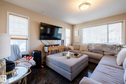 Living area featuring rich dark flooring, neutral wall tones, and multiple windows with blinds - 55 Lamplight Cove, Spruce Grove, AB - Indoor Photo Showing Living Room
