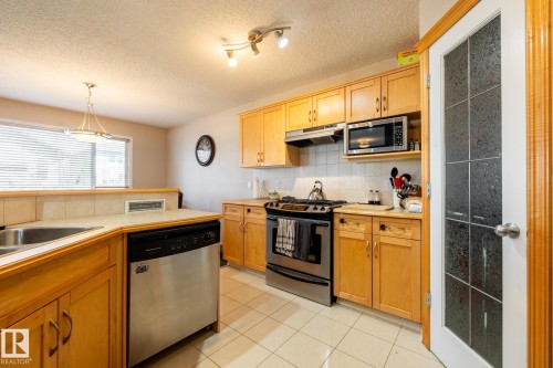Kitchen featuring light wood cabinetry, a stainless steel dishwasher, and a double basin sink - 55 Lamplight Cove, Spruce Grove, AB - Indoor Photo Showing Kitchen With Stainless Steel Kitchen