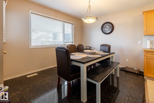Dining area featuring dark-toned flooring, light beige walls, and a large window with blinds - 55 Lamplight Cove, Spruce Grove, AB - Indoor Photo Showing Dining Room