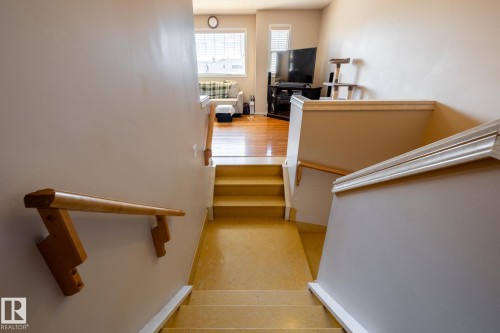 Staircase with light-toned flooring, white risers, and wood handrails - 55 Lamplight Cove, Spruce Grove, AB - Indoor Photo Showing Other Room