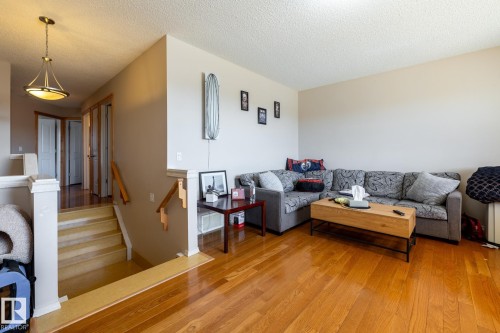 Living area featuring warm wood-finish flooring, neutral painted walls, and a textured ceiling - 55 Lamplight Cove, Spruce Grove, AB - Indoor Photo Showing Living Room