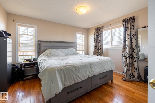 Bedroom featuring warm wood-finish flooring and two windows with blinds - 55 Lamplight Cove, Spruce Grove, AB - Indoor Photo Showing Bedroom