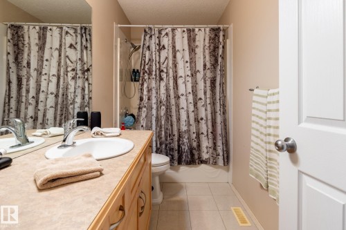 Bathroom featuring a light wood-finish vanity with an integrated basin, a polished chrome faucet, and a full-width mirror - 55 Lamplight Cove, Spruce Grove, AB - Indoor Photo Showing Bathroom