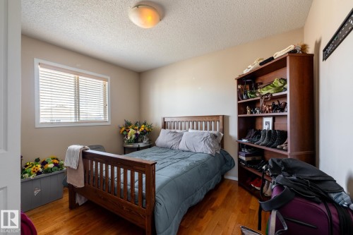 Bedroom featuring wood-finish flooring, neutral wall paint, and a window with horizontal blinds - 55 Lamplight Cove, Spruce Grove, AB - Indoor Photo Showing Bedroom