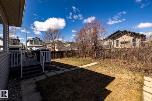 Spacious backyard featuring a wooden deck with railing, a stone-paved pathway, and perimeter fencing - 55 Lamplight Cove, Spruce Grove, AB - Outdoor