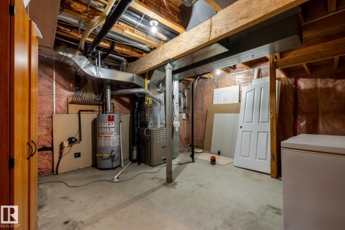 Unfinished basement featuring exposed wood beams, concrete flooring, and an accessible water heater and furnace - 55 Lamplight Cove, Spruce Grove, AB - Indoor Photo Showing Basement