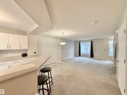 Open-concept living area featuring a kitchen bar, light gray carpet, and multiple windows - 