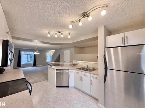 Kitchen featuring light-toned cabinetry, stainless steel appliances, and a double basin sink - 97 465 Hemingway Road, Edmonton, AB - Indoor Photo Showing Kitchen With Stainless Steel Kitchen With Double Sink