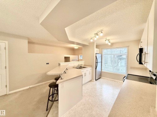 Kitchen area featuring white cabinetry, light-toned countertops, and stainless steel appliances - 97 465 Hemingway Road, Edmonton, AB - Indoor