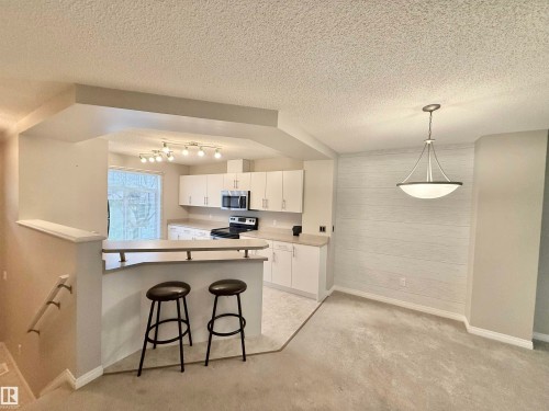 Open-concept kitchen with white cabinetry and a built-in microwave - 97 465 Hemingway Road, Edmonton, AB - Indoor Photo Showing Kitchen
