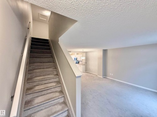 Carpeted staircase with a white handrail - 97 465 Hemingway Road, Edmonton, AB - Indoor Photo Showing Other Room