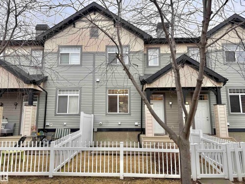 Townhome exterior featuring light gray horizontal siding, dark gray roof, white window frames, and white front doors - 97 465 Hemingway Road, Edmonton, AB - Outdoor