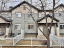 Townhome exterior featuring light gray horizontal siding, dark gray roof, white window frames, and white front doors - 97 465 Hemingway Road, Edmonton, AB  - Outdoor 
