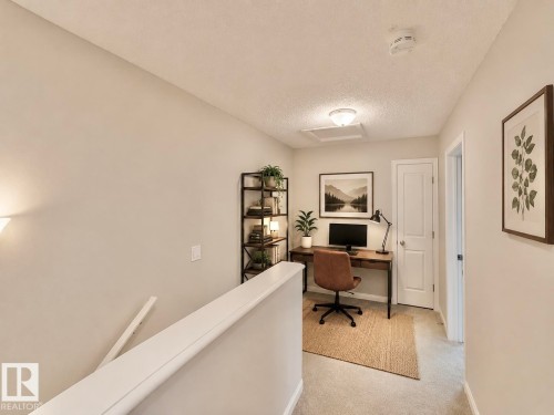 Carpeted hallway with light-toned walls, a white paneled door, and a flush-mount ceiling light - 97 465 Hemingway Road, Edmonton, AB - Indoor Photo Showing Office
