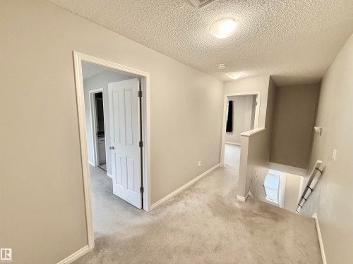 Carpeted hallway with light neutral wall paint and white trim - 97 465 Hemingway Road, Edmonton, AB - Indoor Photo Showing Other Room
