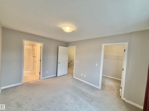 Carpeted interior space featuring light gray wall paint, white trim, a flush mount ceiling light, and multiple doorways - 97 465 Hemingway Road, Edmonton, AB - Indoor Photo Showing Other Room