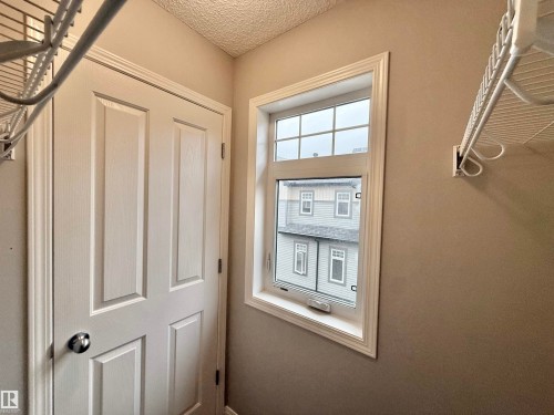 Interior space featuring a white paneled door with chrome hardware, white window trim, and textured ceiling - 97 465 Hemingway Road, Edmonton, AB - Indoor Photo Showing Other Room