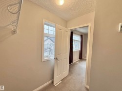 Interior hallway with neutral tone walls and textured ceiling, featuring a wire shelving unit with integrated hanging hooks - 