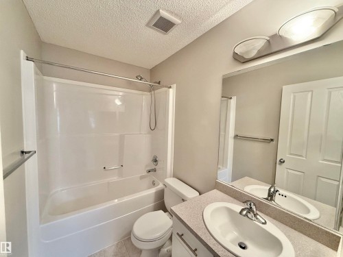 Bathroom featuring a white tub/shower combination, a vanity with an integrated sink, a large wall mirror, and a ceiling-mounted light fixture - 97 465 Hemingway Road, Edmonton, AB - Indoor Photo Showing Bathroom