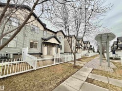 Row of townhomes featuring light siding and dark shingle roofs - 