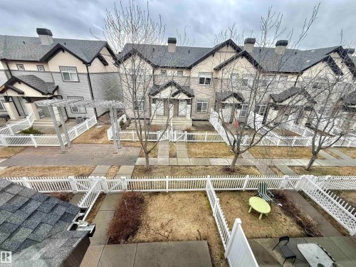 Townhome exterior featuring gabled roofs with dark shingles, light-toned siding, and contrasting dark trim details - 97 465 Hemingway Road, Edmonton, AB - Outdoor