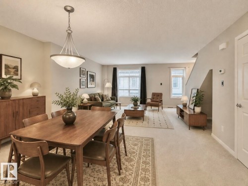 Open-concept living space featuring a dining area with a contemporary chandelier, light-toned walls, and abundant natural light from multiple windows - 97 465 Hemingway Road, Edmonton, AB - Indoor Photo Showing Dining Room