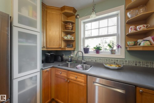 Kitchen featuring wood-finish cabinetry, stainless steel appliances, a double-basin sink, and a tiled backsplash - 11516 72 Avenue, Edmonton, AB - Indoor Photo Showing Kitchen With Double Sink