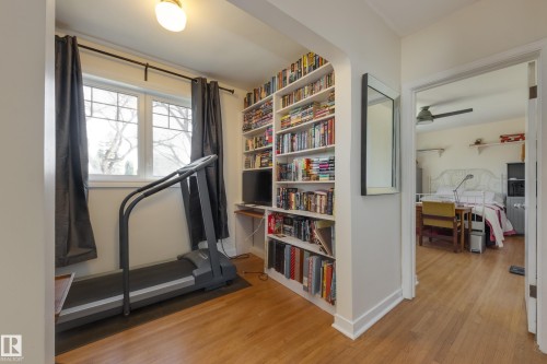 Room featuring wood-finish flooring, a double window with grid panes, a built-in bookshelf, a ceiling-mounted light fixture, and an arched entryway - 11516 72 Avenue, Edmonton, AB - Indoor