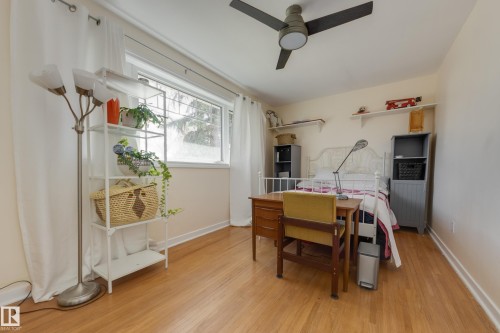 Hardwood-style flooring extends throughout this room, featuring a ceiling fan, a large window, and light-colored walls - 11516 72 Avenue, Edmonton, AB - Indoor