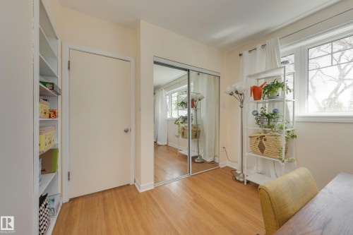 Hardwood flooring throughout, complemented by a large window with white trim - 11516 72 Avenue, Edmonton, AB - Indoor Photo Showing Other Room