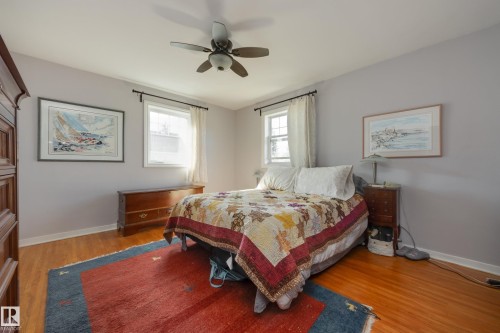 Spacious room featuring wood-finish flooring, light gray walls, and a ceiling fan with integrated lighting - 11516 72 Avenue, Edmonton, AB - Indoor Photo Showing Bedroom