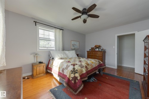 Bedroom featuring wood-finish flooring, light grey painted walls, a window with white trim, and a ceiling fan with integrated lighting - 11516 72 Avenue, Edmonton, AB - Indoor Photo Showing Bedroom